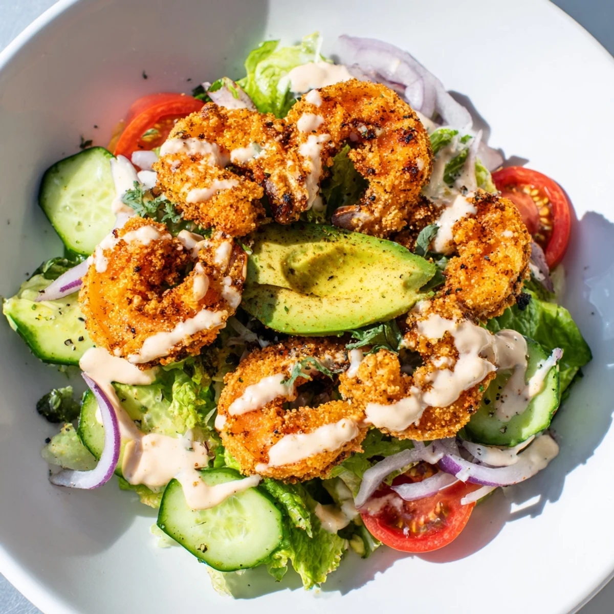 Golden, crispy Spicy Crispy Shrimp Salad sits over fresh greens with creamy avocado and tomatoes.