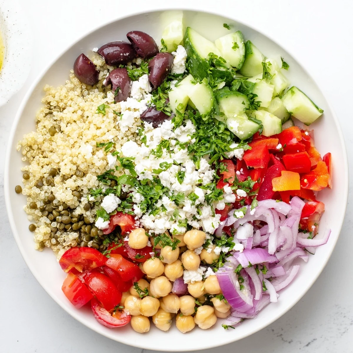 A vibrant Greek Power Salad filled with lentils, quinoa, and chickpeas, topped with fresh vegetables and feta cheese.