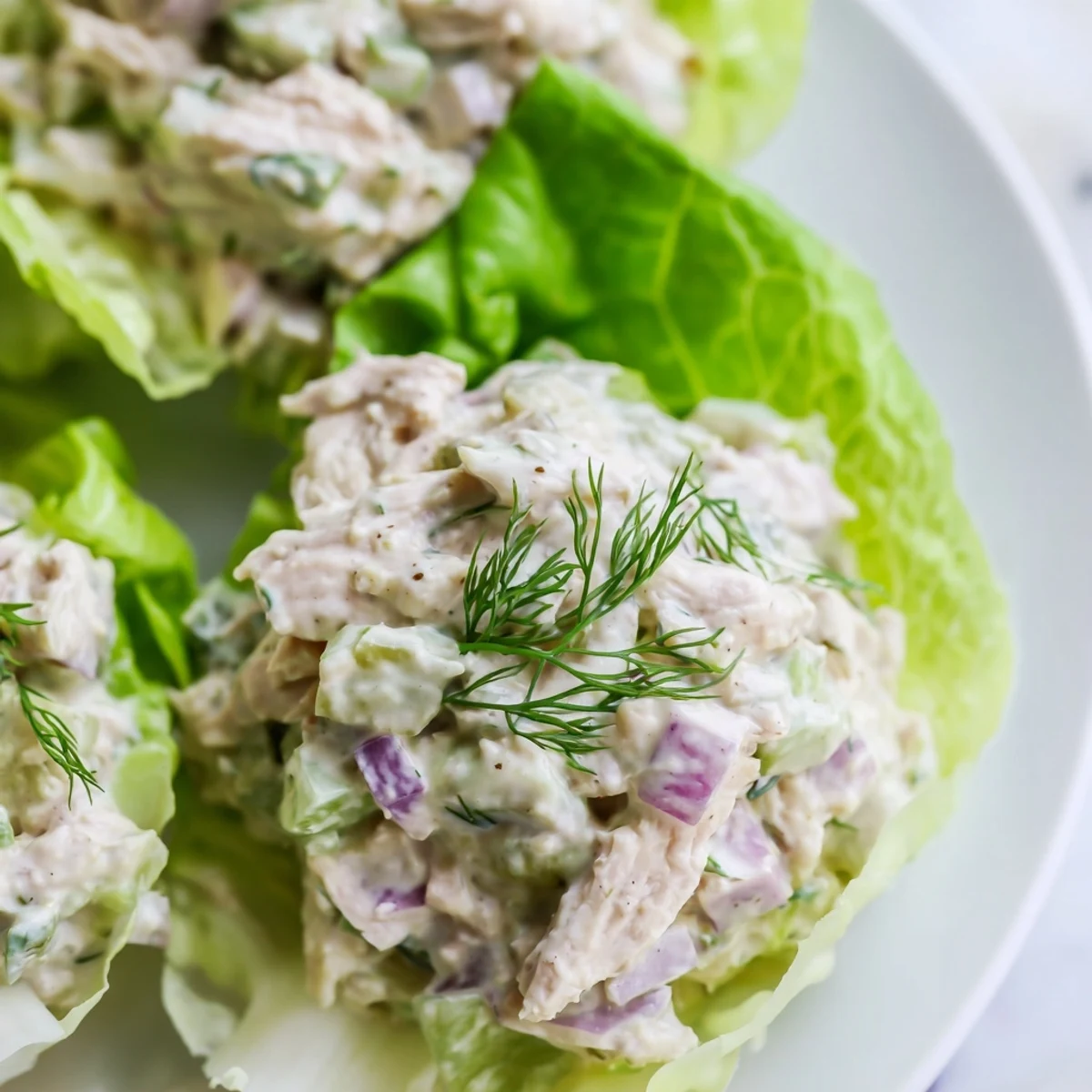 Savory dill pickle chicken salad filling tender lettuce cups, served with a side of extra pickles.