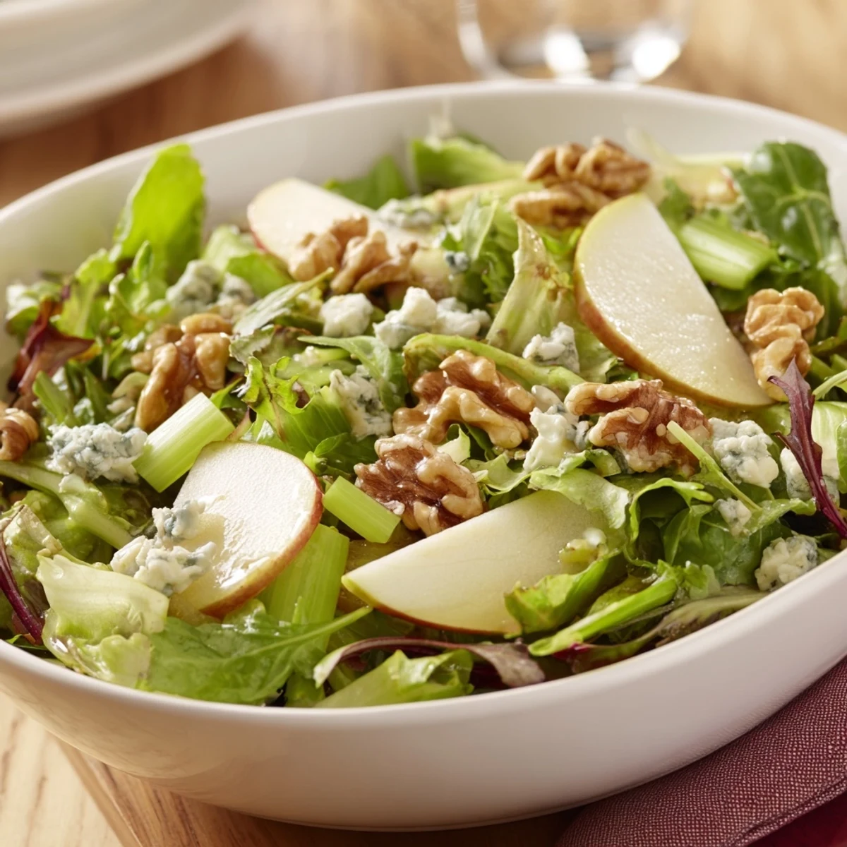 Fresh Apple and Walnut Salad with vibrant apple slices, crunchy walnuts, and a light vinaigrette on a wooden table.
