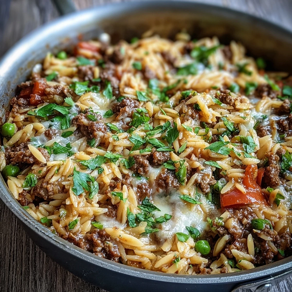 Savory Comforting Ground Beef Orzo Dinner served in a skillet, featuring sweet bell peppers and peas in a rich tomato broth.