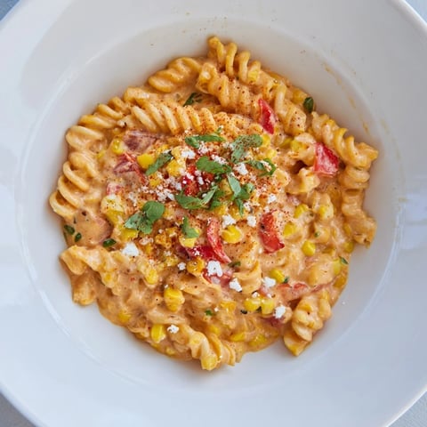 A steaming bowl of one-pot Mexican street corn pasta with vibrant colors and creamy sauce.