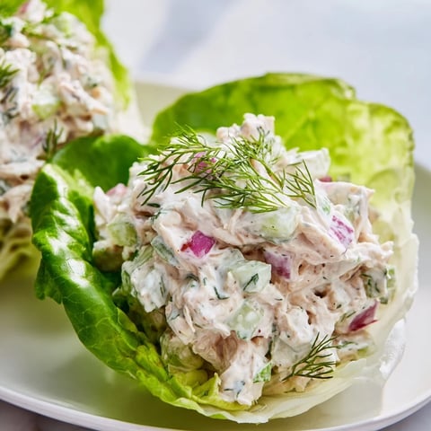 Buttery lettuce cups cradling creamy dill pickle chicken salad, garnished with fresh dill and crisp celery.