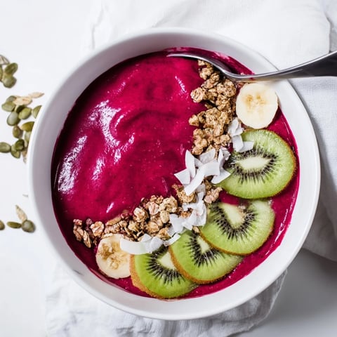 A vibrant Beet and Berry Smoothie Bowl topped with crunchy granola, fresh kiwi, and berries for a nutritious breakfast.