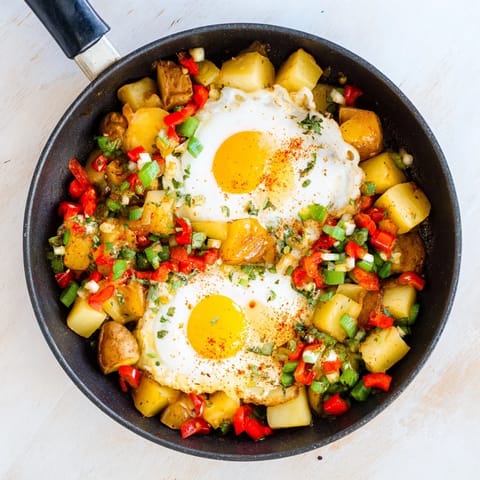 Sizzling skillet egg and potato hash with vibrant bell peppers: a hearty breakfast or dinner.