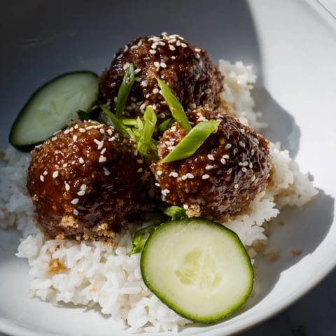 Steaming teriyaki meatball bowls, savory meatballs coated in glossy sauce atop fluffy rice, very appealing.