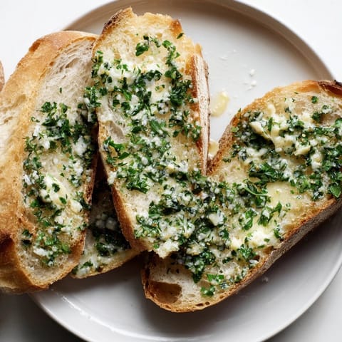 Freshly toasted Herb Butter Toast is arranged on a white plate, topped with bright green parsley, chives, and aromatic garlic butter.  