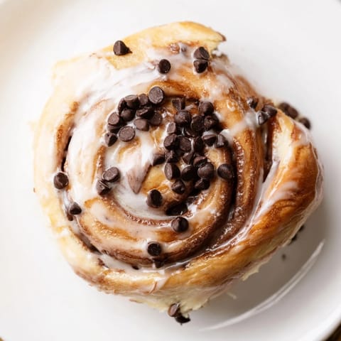 A close-up of freshly baked Nutella Chocolate Chip Rolls in a 9x13 pan, showcasing melty chocolate chips and a rich, nutty swirl.  
