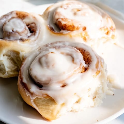 Golden-brown Pillow Soft Cinnamon Rolls fresh from the oven, drizzled with a rich cream cheese glaze and perfect for a cozy breakfast.  