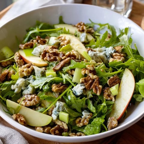 Apple and Walnut Salad served in a rustic bowl, featuring crumbled blue cheese, mixed greens, and a honey-Dijon dressing.  