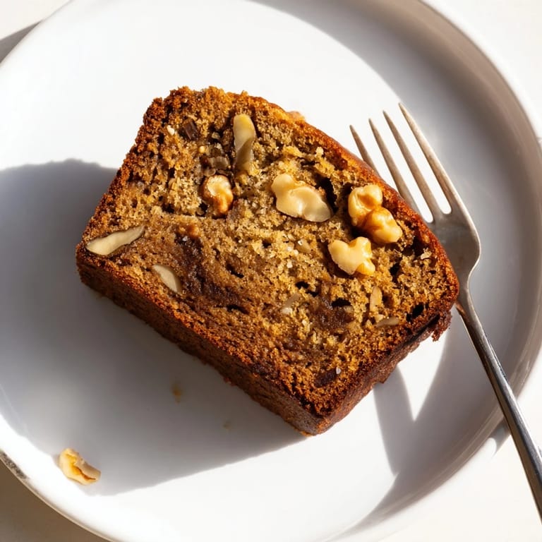 Perfectly baked classic banana bread, topped with a pat of butter melting into the tender, moist crumb.