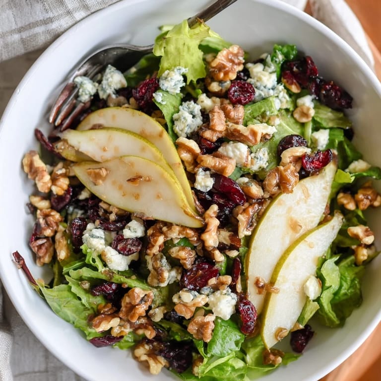 Juicy pear slices and tangy Gorgonzola cheese rest on crisp greens, drizzled with honey-balsamic vinaigrette in this vibrant Pear Gorgonzola Salad.